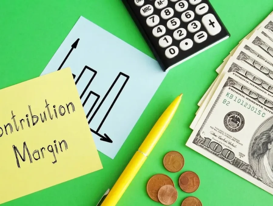 Contribution Margin" written on a sticky note next to a calculator, chart, and dollar bills on a green background.